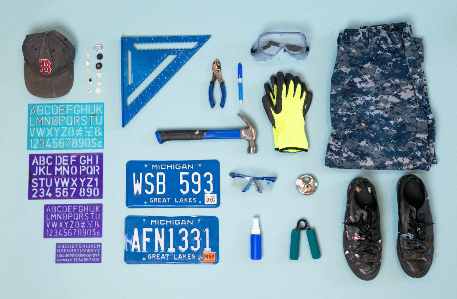 Tools, clothing, and license plates arranged flat lay.